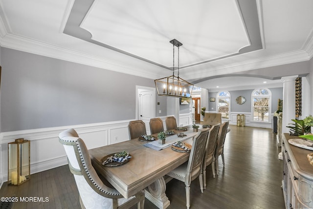 dining room with a notable chandelier, ornamental molding, dark hardwood / wood-style flooring, a raised ceiling, and ornate columns