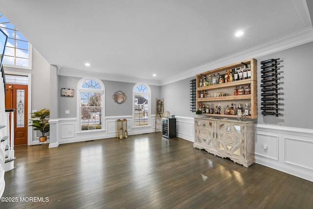 unfurnished living room with dark hardwood / wood-style floors, ornamental molding, and bar area