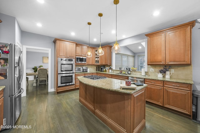 kitchen featuring sink, light stone counters, decorative light fixtures, a center island, and appliances with stainless steel finishes