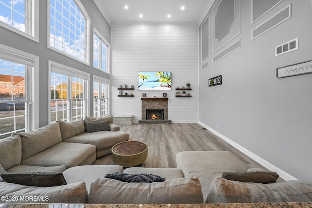 living room featuring ornamental molding, a towering ceiling, and light hardwood / wood-style floors