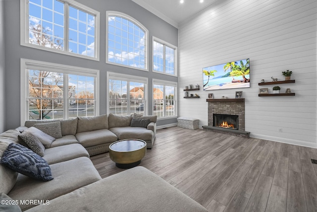 living room featuring hardwood / wood-style flooring, a fireplace, crown molding, and a high ceiling