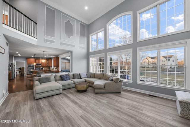 living room featuring light hardwood / wood-style flooring, ornamental molding, and a high ceiling