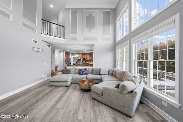 living room with crown molding, plenty of natural light, and light hardwood / wood-style flooring