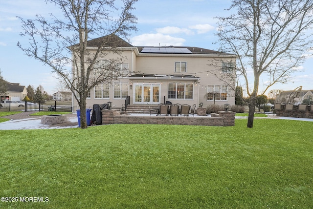 back of house with an outdoor fire pit, a lawn, a patio area, and solar panels