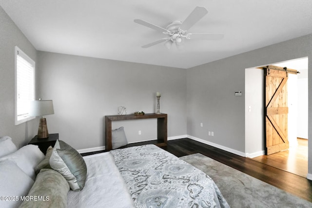 bedroom with a barn door, dark wood-type flooring, and ceiling fan