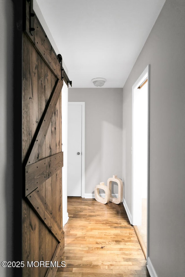 corridor featuring a barn door and light wood-type flooring