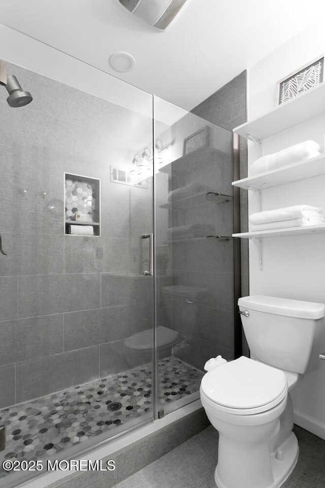 bathroom with a shower with door and toilet