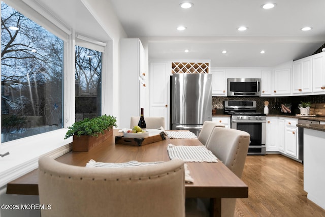 kitchen with decorative backsplash, stainless steel appliances, light hardwood / wood-style flooring, and white cabinets