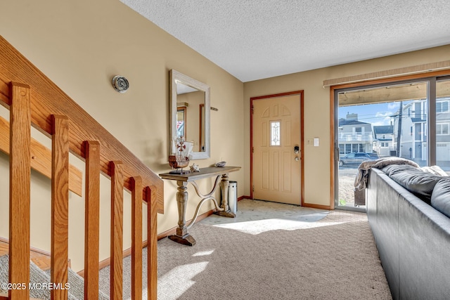 foyer entrance with a textured ceiling and light colored carpet