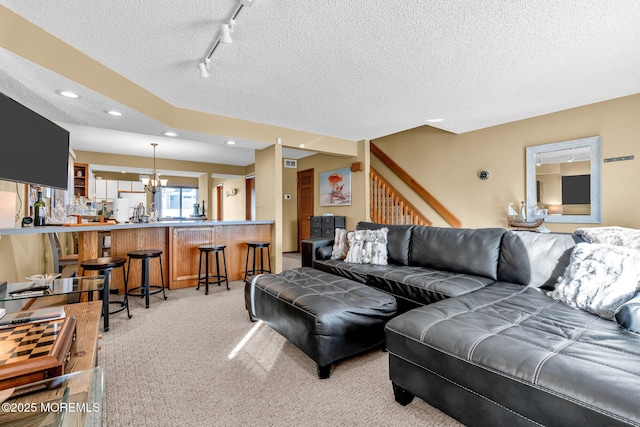 carpeted living room featuring a textured ceiling, track lighting, and a notable chandelier