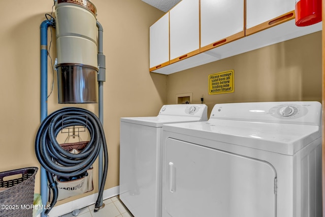 laundry room with washing machine and clothes dryer, a textured ceiling, light tile patterned floors, and cabinets