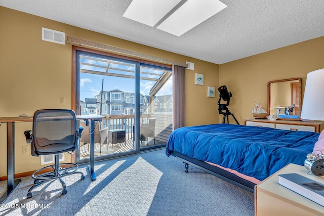 bedroom with a textured ceiling, carpet, access to exterior, and a skylight