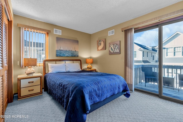 bedroom with light carpet, access to outside, a textured ceiling, and multiple windows