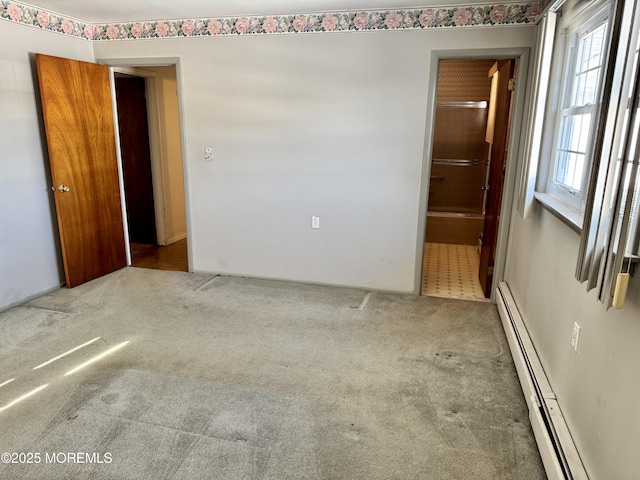 carpeted empty room with a baseboard heating unit