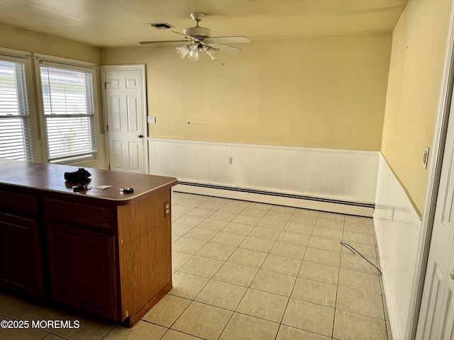 kitchen with ceiling fan, light tile patterned floors, and a baseboard heating unit