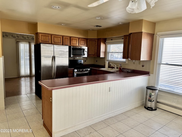 kitchen with sink, kitchen peninsula, light tile patterned floors, and stainless steel appliances