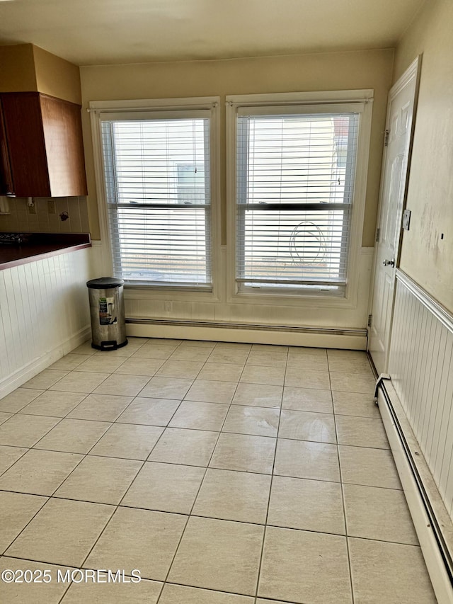 unfurnished dining area featuring light tile patterned floors and baseboard heating