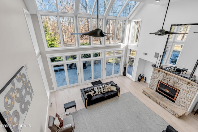 living room featuring a fireplace, light hardwood / wood-style floors, and a towering ceiling