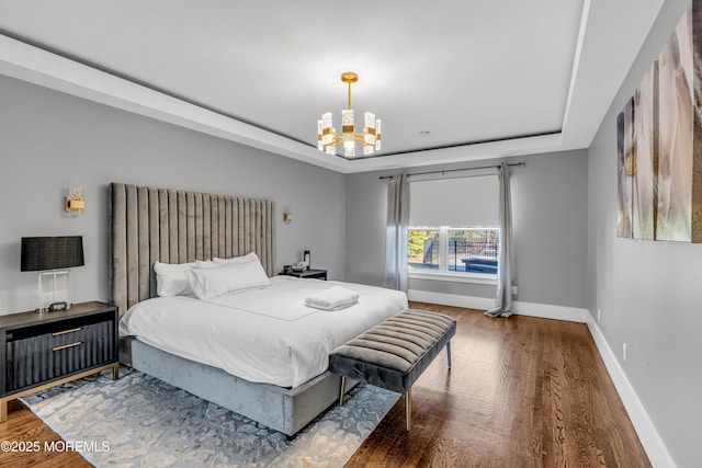 bedroom featuring hardwood / wood-style floors, a tray ceiling, and a notable chandelier