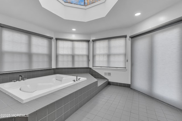 bathroom with tiled tub, tile patterned floors, and a skylight