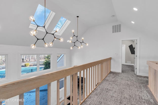 hall featuring carpet flooring, a healthy amount of sunlight, and vaulted ceiling with skylight