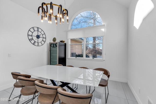 tiled dining area with high vaulted ceiling, a healthy amount of sunlight, and an inviting chandelier