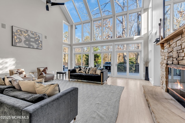 living room with high vaulted ceiling, light hardwood / wood-style floors, and a fireplace