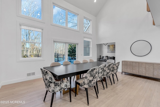 dining space with light wood-type flooring and high vaulted ceiling