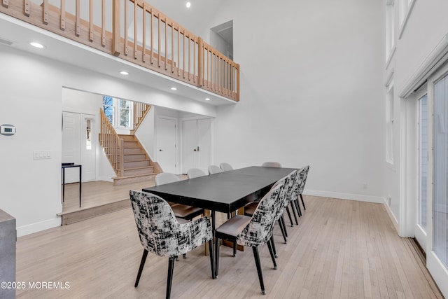 dining area featuring light hardwood / wood-style flooring and a towering ceiling