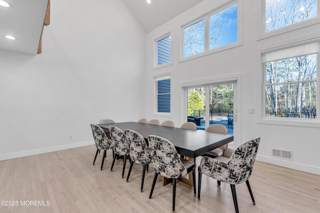 dining space featuring high vaulted ceiling and light hardwood / wood-style floors