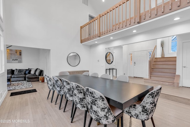 dining room featuring a towering ceiling and light wood-type flooring