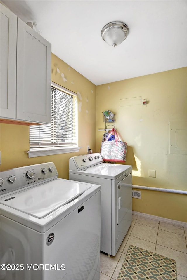 washroom featuring cabinets, washing machine and dryer, and light tile patterned floors