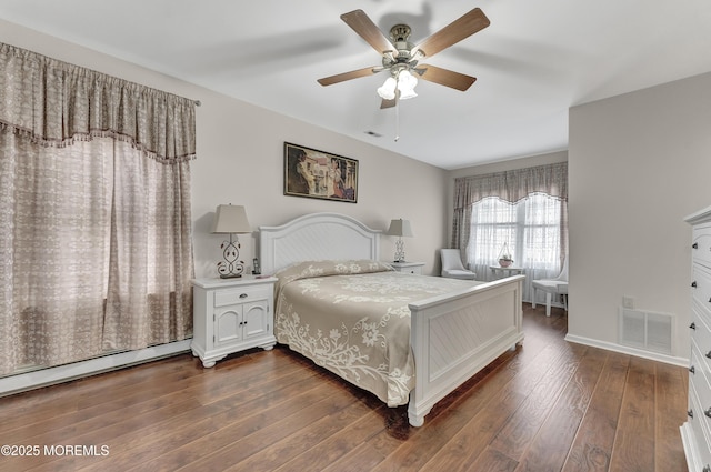 bedroom with ceiling fan, a baseboard heating unit, and dark wood-type flooring