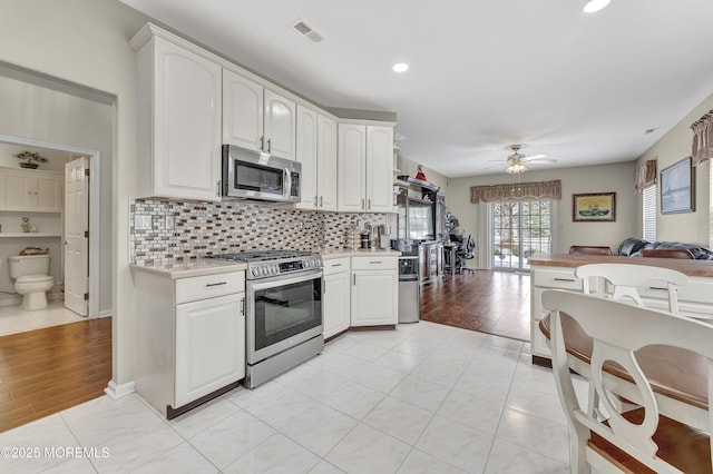 kitchen with light tile patterned flooring, tasteful backsplash, white cabinetry, and stainless steel appliances