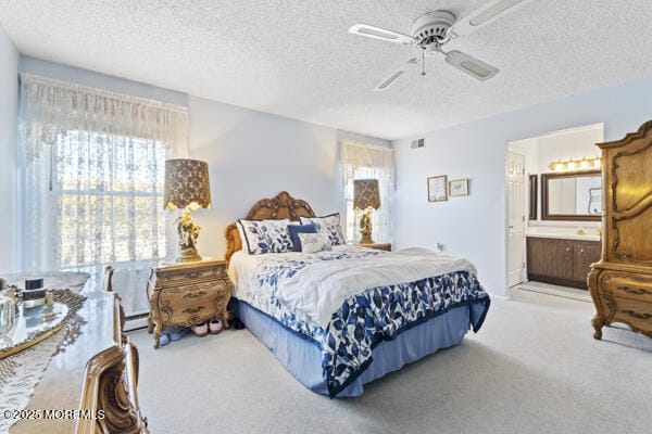 carpeted bedroom featuring ensuite bathroom, a textured ceiling, and ceiling fan