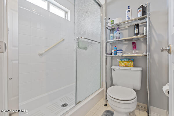 bathroom featuring toilet, tile patterned floors, and walk in shower