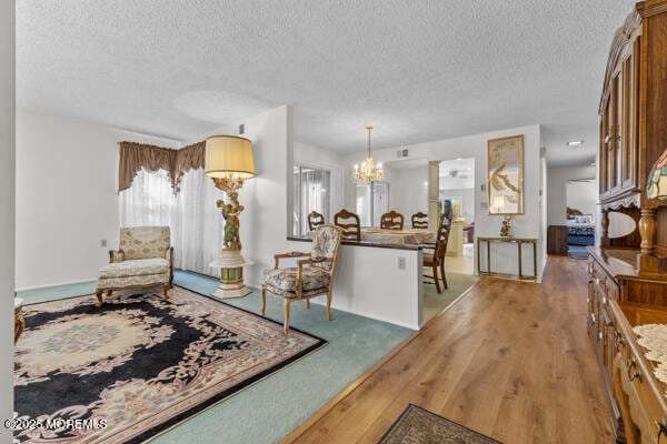 living room featuring light wood-type flooring, a textured ceiling, and an inviting chandelier