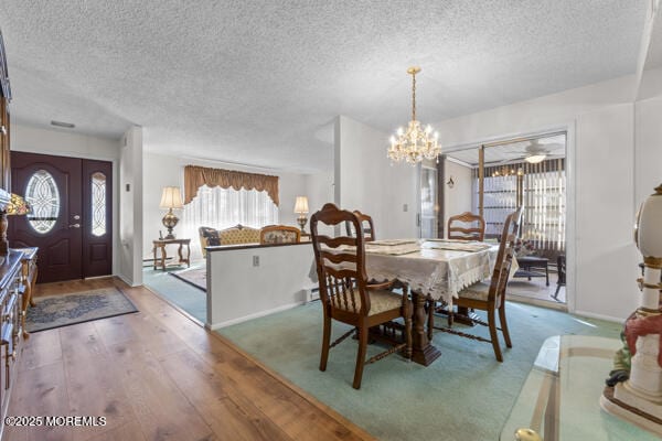 dining area featuring hardwood / wood-style floors, a notable chandelier, and a textured ceiling