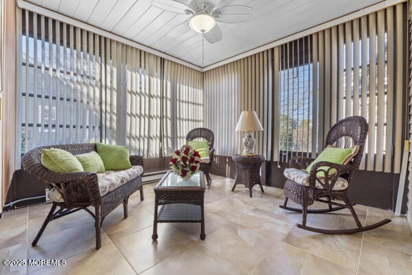 sunroom / solarium featuring a baseboard heating unit and ceiling fan