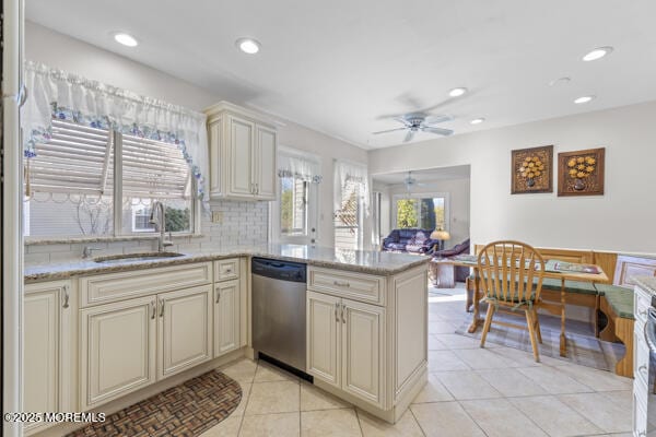 kitchen featuring sink, dishwasher, kitchen peninsula, cream cabinets, and backsplash