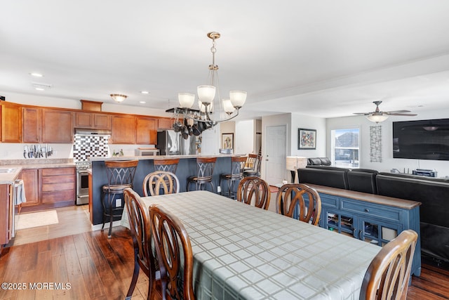 dining room with sink, hardwood / wood-style flooring, and ceiling fan with notable chandelier