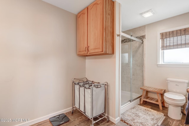 bathroom with toilet, an enclosed shower, and wood-type flooring