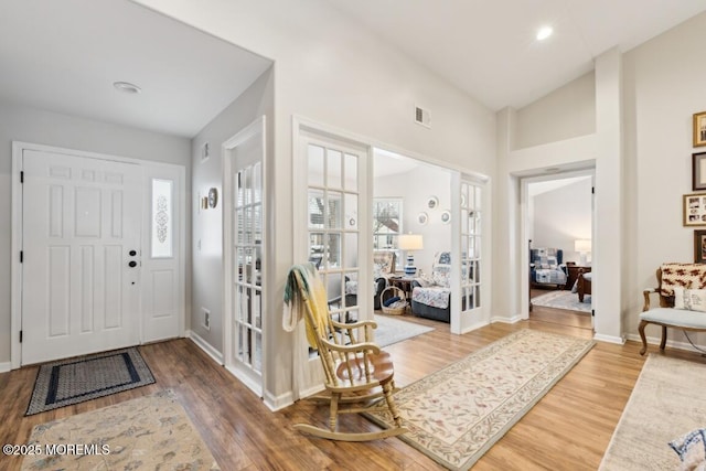 foyer with wood-type flooring, vaulted ceiling, and french doors