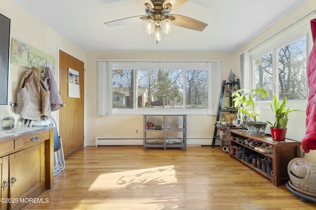 interior space with a baseboard heating unit, light hardwood / wood-style flooring, and ceiling fan