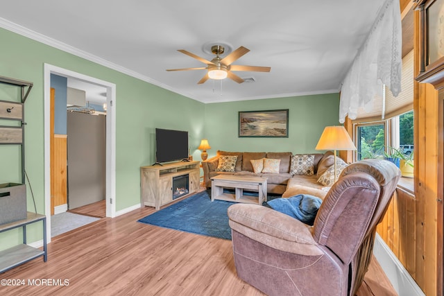 living room featuring ceiling fan, light hardwood / wood-style flooring, ornamental molding, and a fireplace