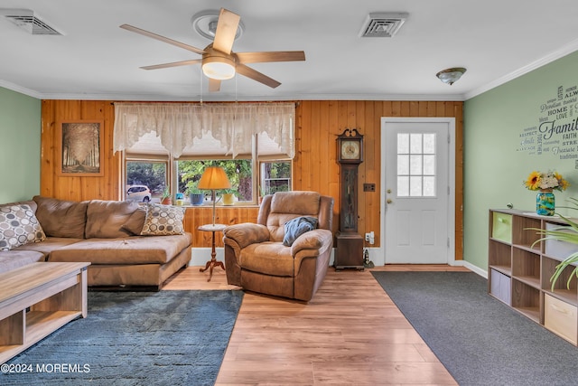 living room with crown molding, hardwood / wood-style floors, wooden walls, and a wealth of natural light