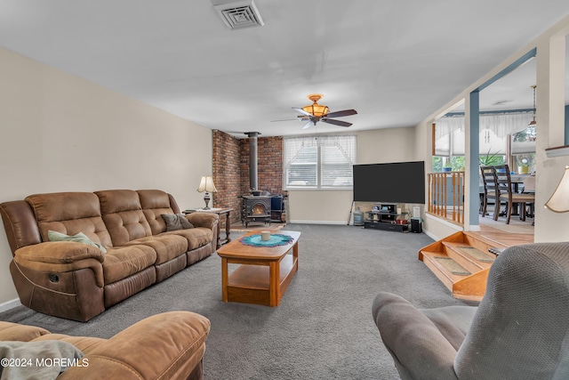 living room featuring a wood stove, carpet, and ceiling fan