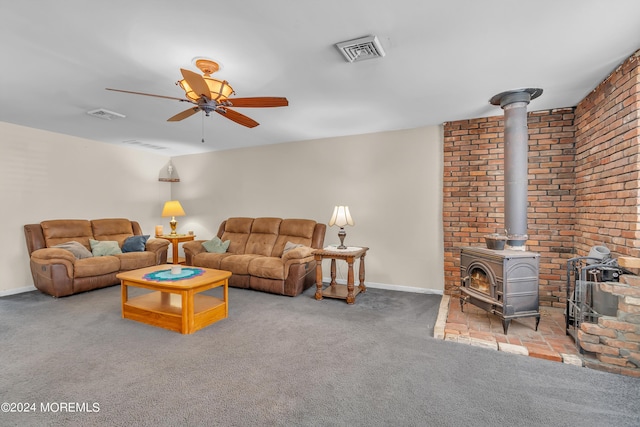 carpeted living room featuring a wood stove and ceiling fan