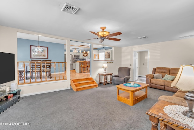 carpeted living room with ceiling fan with notable chandelier