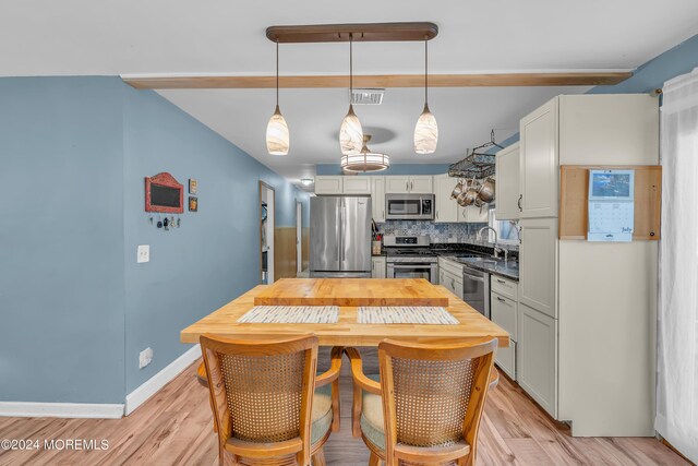 kitchen featuring backsplash, pendant lighting, light wood-type flooring, and stainless steel appliances